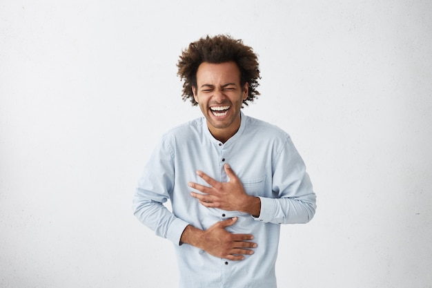 Hombre afroamericano positivo y alegre con una fina mata de pelo riendo a carcajadas