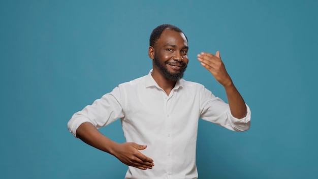 Hombre afroamericano que muestra movimientos de baile robot en el estudio, haciendo bailes de fiesta únicos y movimiento en la música urbana contemporánea. Artista masculino moviéndose en sonido disco con acción robótica.