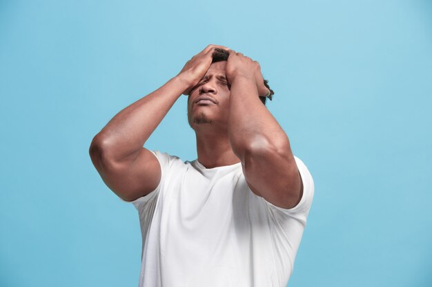 Hombre afroamericano que tiene dolor de cabeza. Aislado sobre fondo azul