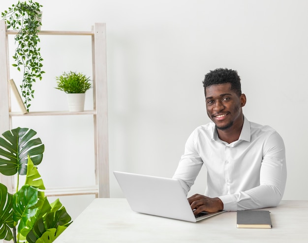 Hombre afroamericano sentado en el escritorio y sonríe