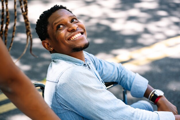 Un hombre afroamericano en silla de ruedas disfrutando de un paseo al aire libre con su novia