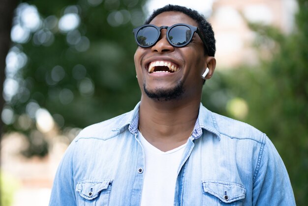 Hombre afroamericano sonriendo mientras está de pie al aire libre en la calle