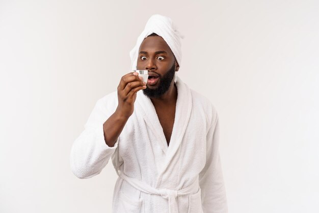 Hombre afroamericano sonriente aplicando crema en su rostro Concepto de cuidado de la piel del hombre