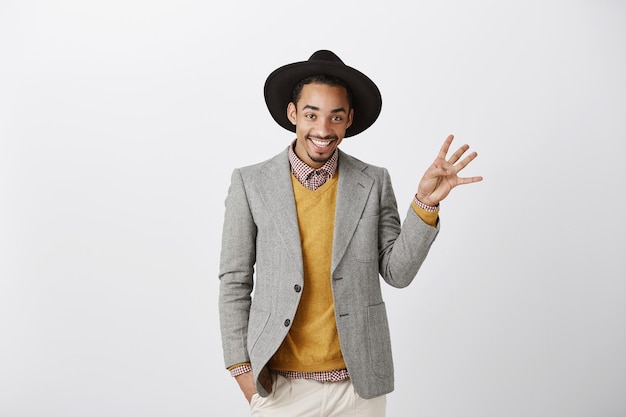 Hombre afroamericano sonriente hermoso en traje elegante que muestra el número cuatro, haciendo orden