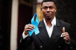 Foto gratuita hombre afroamericano sostenga la cinta azul de la próstata concientización sobre el cáncer de la salud de los hombres