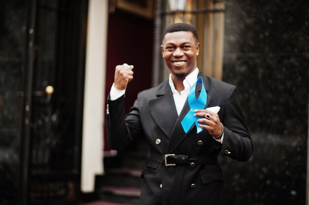 Hombre afroamericano sostenga la cinta azul de la próstata Concientización sobre el cáncer de la salud de los hombres