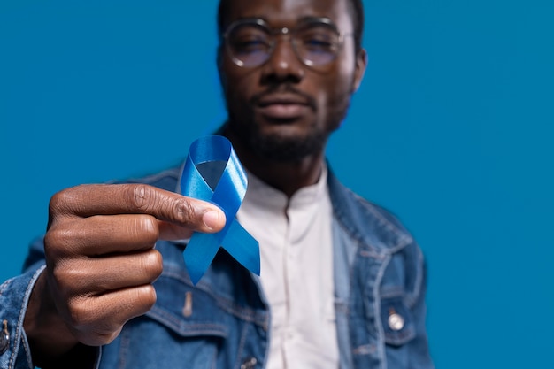 Hombre afroamericano sosteniendo una cinta azul