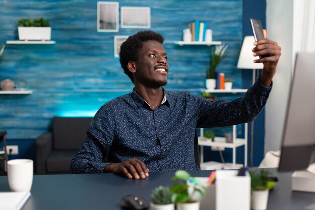 Hombre afroamericano tomando selfie en acogedora sala de estar