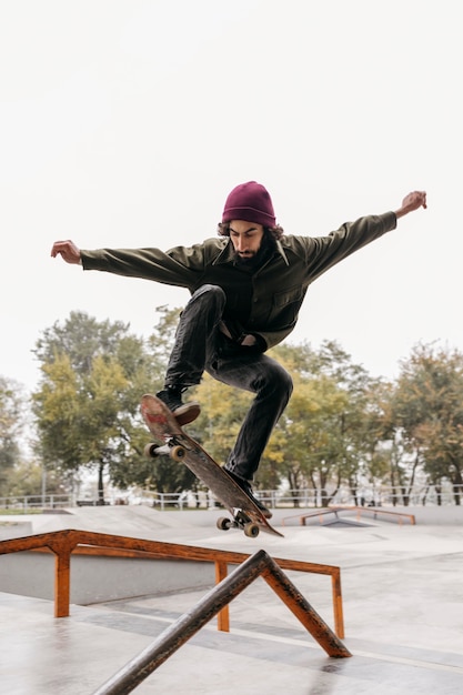 Foto gratuita hombre afuera con patineta en el parque de la ciudad