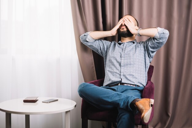 Hombre agotado sentado en el sillón