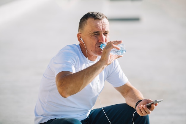 Foto gratuita hombre agua potable con auriculares en sus oídos