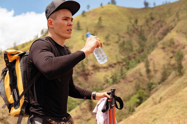 Hombre agua potable trekking en las montañas. bali