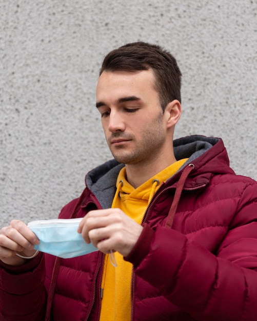 Foto gratuita hombre al aire libre poniéndose mascarilla médica