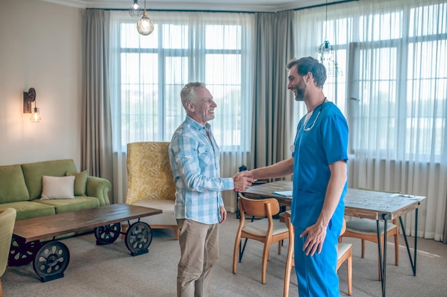 Hombre alegre agitando la mano de su médico