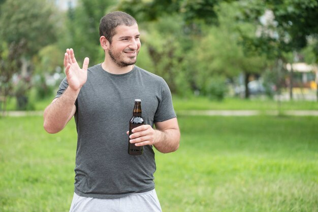 Hombre alegre con cerveza agitando la mano