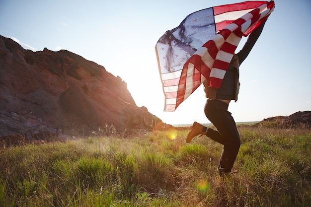 Hombre alegre corriendo con bandera de Estados Unidos