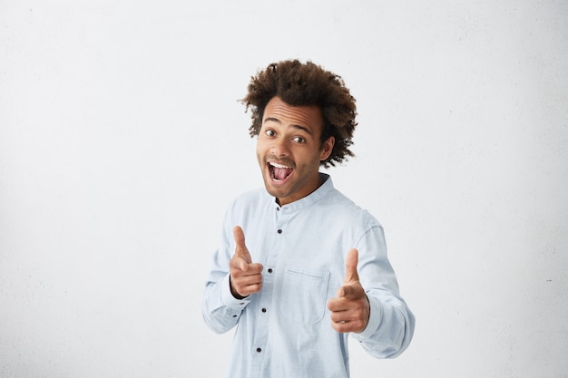 Hombre alegre emocionado con camisa azul claro levantando las cejas y exclamando