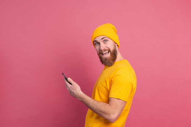 Hombre alegre feliz guapo europeo con teléfono móvil sonriendo en rosa