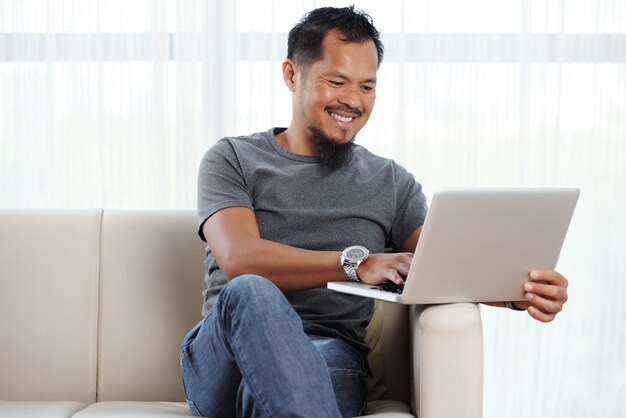 Hombre alegre filipino con laptop