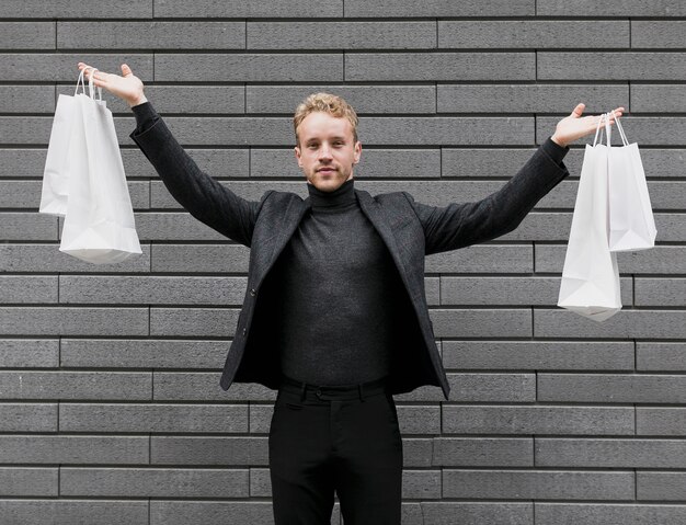 Hombre alegre levantando las bolsas de compras