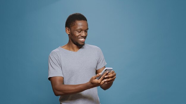 Hombre alegre leyendo buenas noticias y logros en el teléfono inteligente, celebrando la victoria y el logro exitosos. Adulto que se siente feliz y complacido por el éxito y la victoria, navegando por Internet por teléfono.