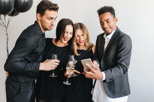 Hombre alegre mostrando las últimas fotos de amigos en su teléfono durante la fiesta