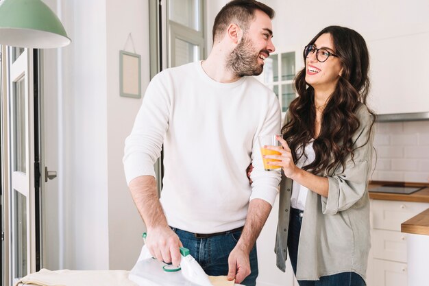 Hombre alegre y mujer planchando en casa