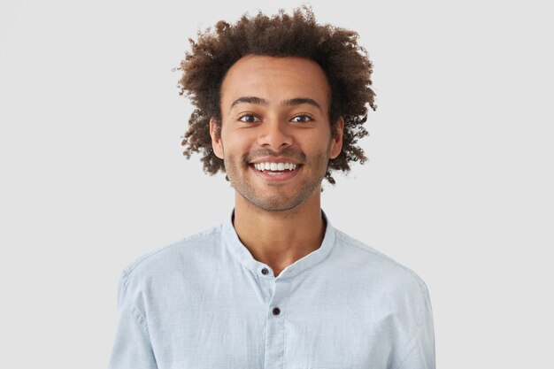 Hombre alegre positivo alegre tiene amplia sonrisa, se regocija en la promoción en el trabajo