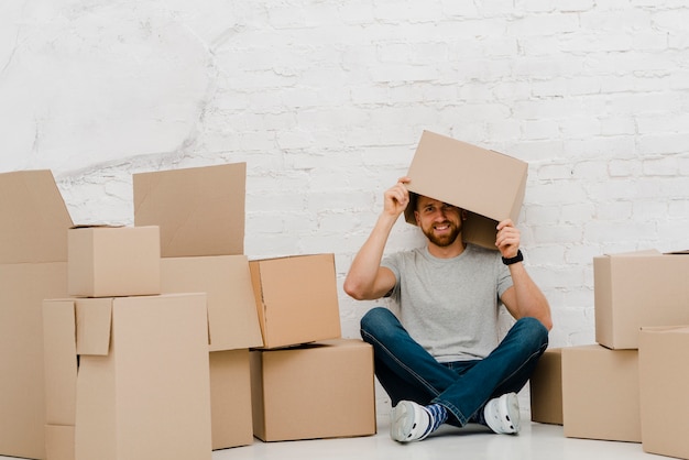 Foto gratuita hombre alegre que pone la caja en la cabeza