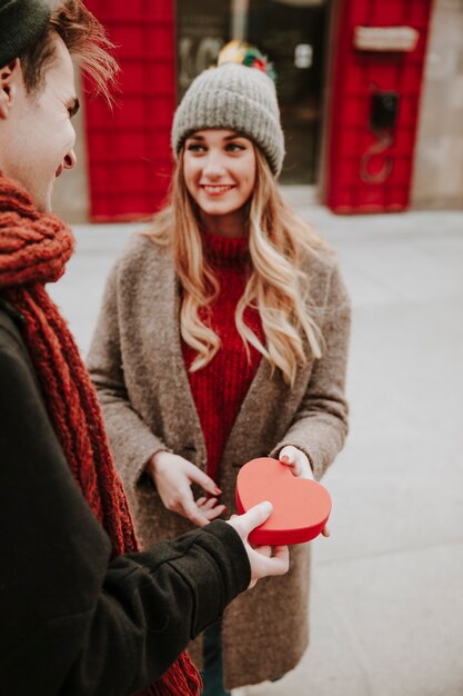 Hombre alegre que regala la caja del corazón a la novia