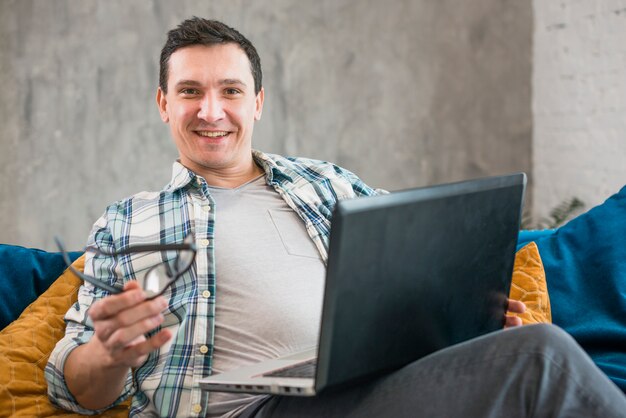 Hombre alegre que trabaja en la computadora portátil en casa