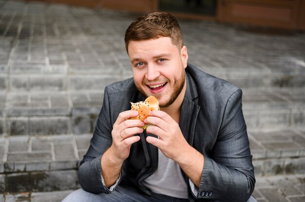 Hombre alegre sentado con comida en sus manos