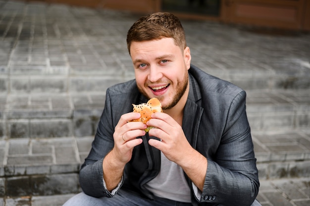 Hombre alegre sentado con comida en sus manos