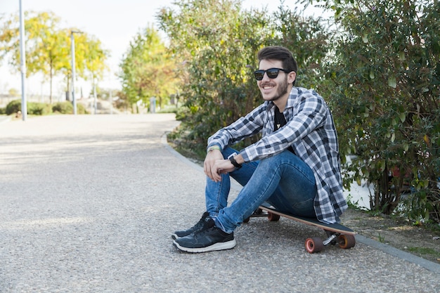 Hombre alegre sentado en longboard