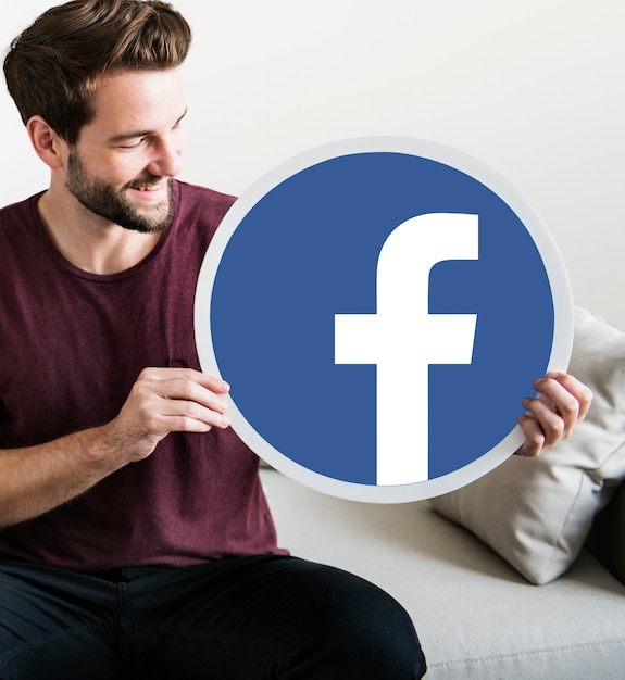 Hombre alegre sosteniendo un icono de Facebook