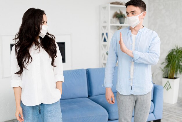 Hombre alejado de la mujer con mascarilla