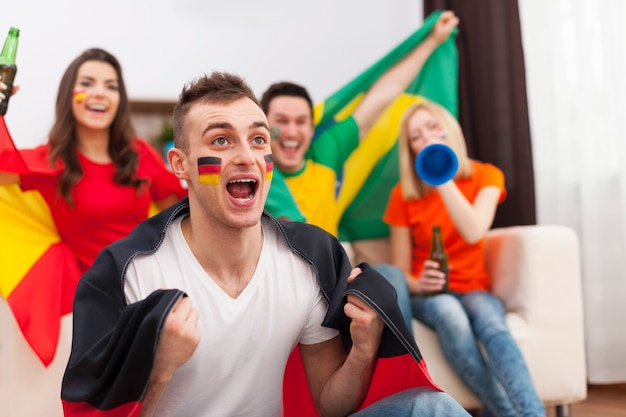 Foto gratuita hombre alemán emocionado con sus amigos animando partido de fútbol