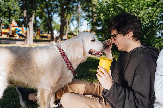 El hombre alimenta a su perro bocadillos por obediencia en el parque, vista cercana