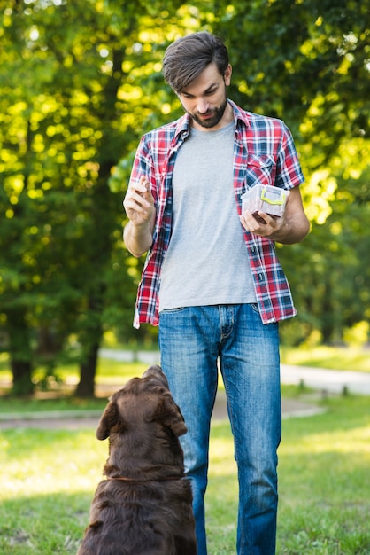 Hombre alimentando comida a su perro en el jardín