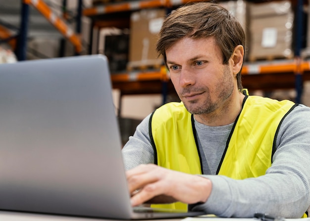 Foto gratuita hombre en almacén trabajando en equipo portátil