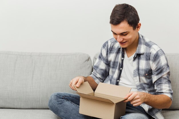 Hombre de alto ángulo en la caja de apertura del sofá