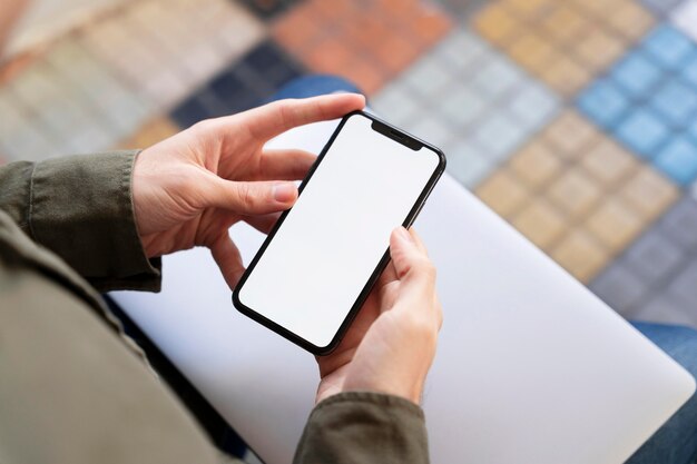 Hombre de alto ángulo mirando su teléfono con pantalla vacía