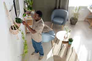 Foto gratuita hombre de alto ángulo regando plantas en casa