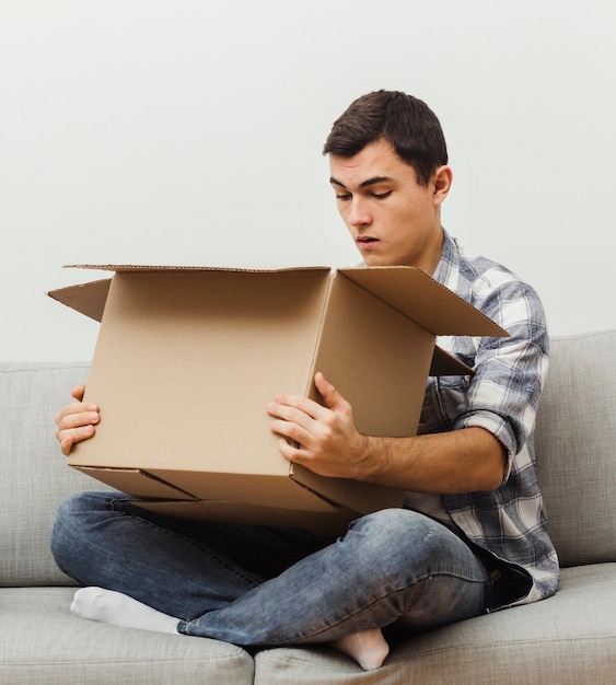 Hombre de alto ángulo sorprendido del contenido de la caja