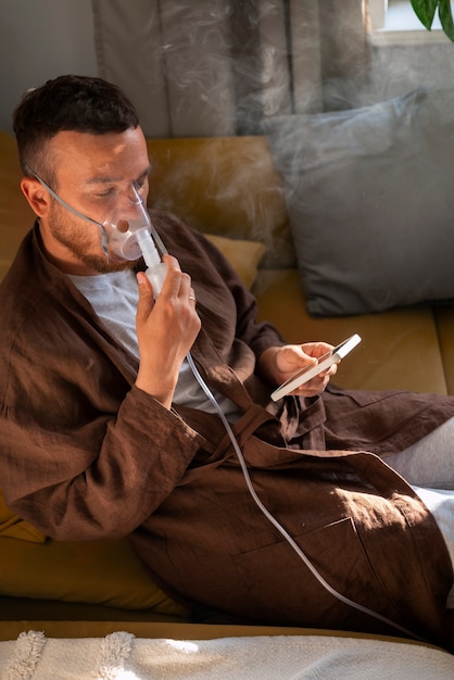 Foto gratuita hombre de alto ángulo usando un nebulizador