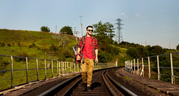 Hombre de ángulo bajo caminando sobre el riel del tren