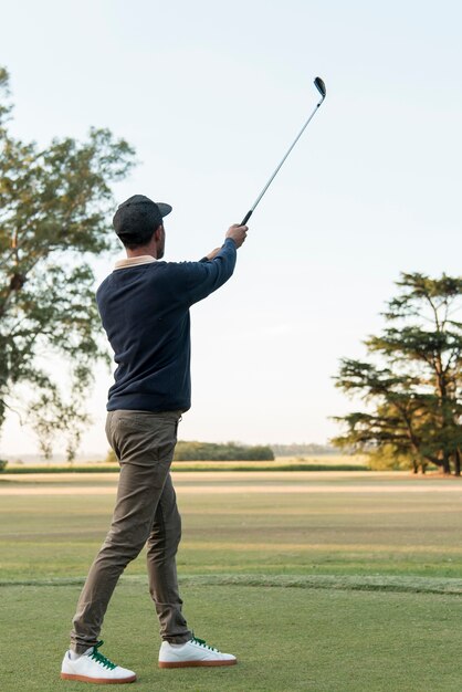 Hombre de ángulo bajo jugando al golf