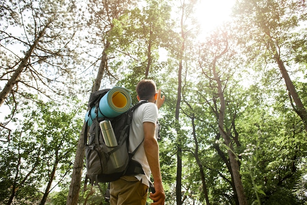 Hombre de ángulo bajo con mochila en bosque