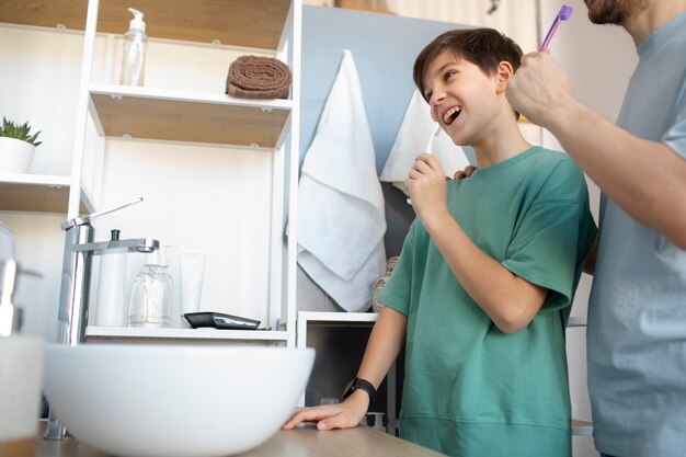 Hombre de ángulo bajo y niño cepillando los dientes