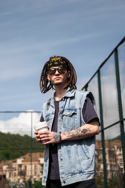 Hombre de ángulo bajo con rastas afro posando